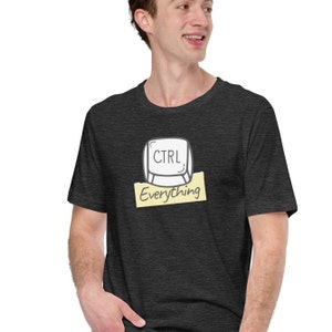 May include: Dark gray t-shirt featuring a cartoon keyboard key with the word "CTRL" and the word "Everything" below it. The design is in black and white on a yellow rectangle. The shirt is short-sleeved.