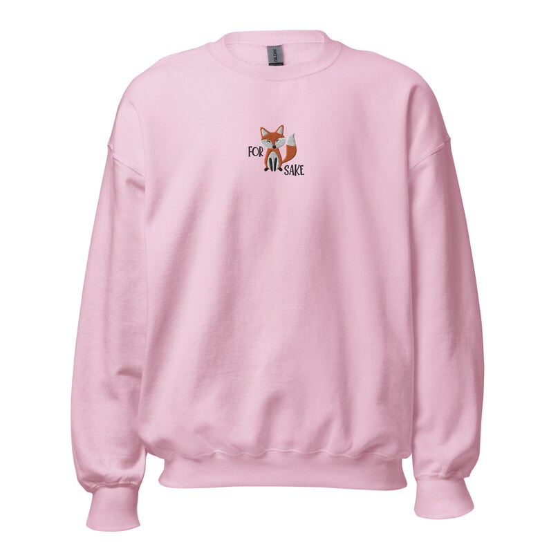 Pu&ograve; includere: Una felpa rosa con una volpe di cartone animato e il testo "FOR FOX SAKE" ricamato sul davanti.