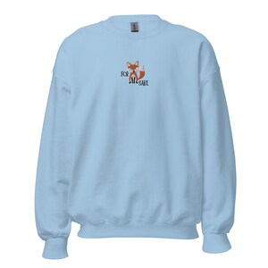 Pu&ograve; includere: Una felpa di colore azzurro chiaro con una piccola volpe ricamata e il testo "FOR FOX SAKE" sul davanti.