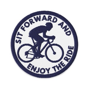 May include: A navy blue embroidered patch with a white background. The patch features a silhouette of a person riding a bicycle with the text "Sit forward and enjoy the ride".