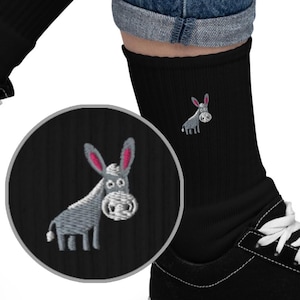 Könnte beinhalten: Schwarze Socken mit einem gestickten grauen Esel. Der Esel hat rosa Ohren und ein weißes Gesicht.