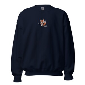 Pu&ograve; includere: Una felpa blu navy con una piccola volpe ricamata e il testo "FOR FOX SAKE" sul davanti.