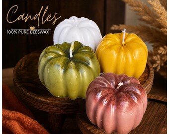 Puede incluir: Cuatro velas con forma de calabaza hechas de cera de abeja 100% pura en blanco, verde oliva, amarillo y granate. El texto PUMPKIN Candles 100% PURE BEESWAX es visible. Cada vela presenta una mecha central y una superficie exterior redondeada.