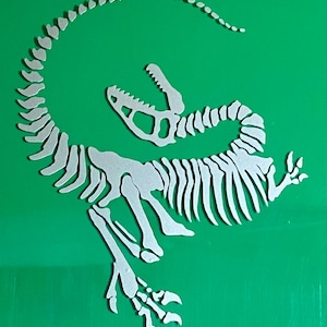 Puede incluir: Un recorte de esqueleto de dinosaurio blanco sobre un fondo verde brillante. El recorte representa un dinosaurio estilizado con cola curva, boca abierta y estructura ósea detallada. El diseño es un elemento decorativo.