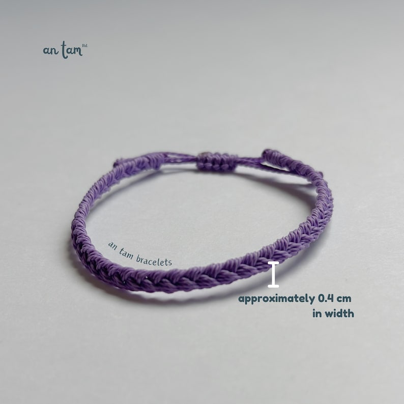 May include: A braided lavender bracelet with an adjustable knot closure. The bracelet is approximately 0.4 cm in width. The text "an tam bracelets" is visible. The brand name "an tam" is also visible.