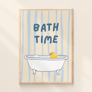 Op de afbeelding: Een ingelijste print met de woorden "BATH TIME" in blauwe letters boven een witte badkuip met een gele badeend. De achtergrond heeft verticale blauwe strepen op een beige achtergrond.