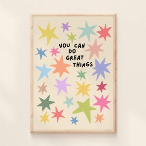 May include: A rectangular wall art print featuring a cream background with numerous multi-colored stars in shades of yellow, pink, blue, green, and orange. The text "YOU CAN DO GREAT THINGS" is printed in the center in a bold, black, sans-serif font.