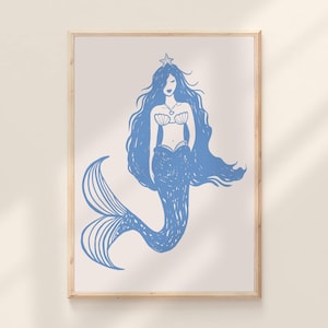 May include: A framed print featuring a blue mermaid illustration. The mermaid has long flowing hair, a star-shaped crown, and a seashell bra. The mermaid's tail is detailed with curved lines. The artwork is set against a cream background.
