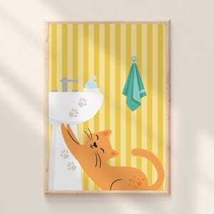 Op de afbeelding: Een ingelijste illustratie met een cartoon oranje kat die uitreikt naar een witte wastafel met pootafdrukken. De achtergrond heeft gele verticale strepen, een turquoise handdoek en een kraan.