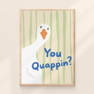 Pode incluir: Impressão de arte emoldurada com um ganso branco, bico laranja e o texto azul "You Quappin?". O fundo tem listras verticais verdes sobre um fundo bege. A obra de arte está em uma moldura de madeira.