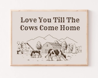 May include: A brown wooden framed print with a white background. The print features a black and white illustration of a farm scene with two cows, a barn, and hay bales. The text "Love You Till The Cows Come Home" is printed in brown at the top of the print.