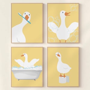 Puede incluir: Conjunto de cuatro láminas enmarcadas con dibujos de gansos en varias escenas de baño. Un ganso se cepilla los dientes, otro está en una bañera y otros dos posan. El fondo es de color amarillo liso.