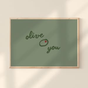 Puede incluir: Una impresión artística enmarcada con un fondo verde. Las palabras "olive you" están escritas en una fuente cursiva. La "o" en "olive" se reemplaza con una aceituna con un corazón rojo.