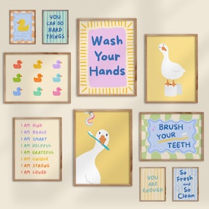 May include: A collection of framed wall art with a light wood finish. The art features ducks, geese, and motivational phrases like "Wash Your Hands" and "Brush Your Teeth." The color palette includes yellow, blue, and pink.