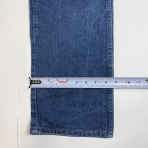 May include: Close-up of blue denim jeans with a measuring tape showing a width of approximately 17.8 cm. The jeans are on a white surface. The tape measure is labeled "Kobalt".