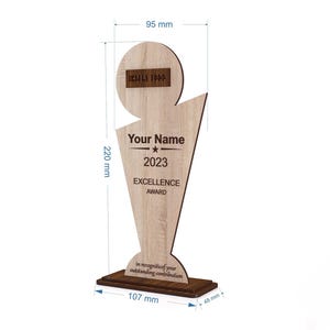 May include: A wooden Excellence Award trophy, 220 mm tall, with a light wood grain finish. It features the text "Your Name", "2023", and "EXCELLENCE AWARD". The base is 107 mm wide and 48 mm deep. The top has a space for a logo.