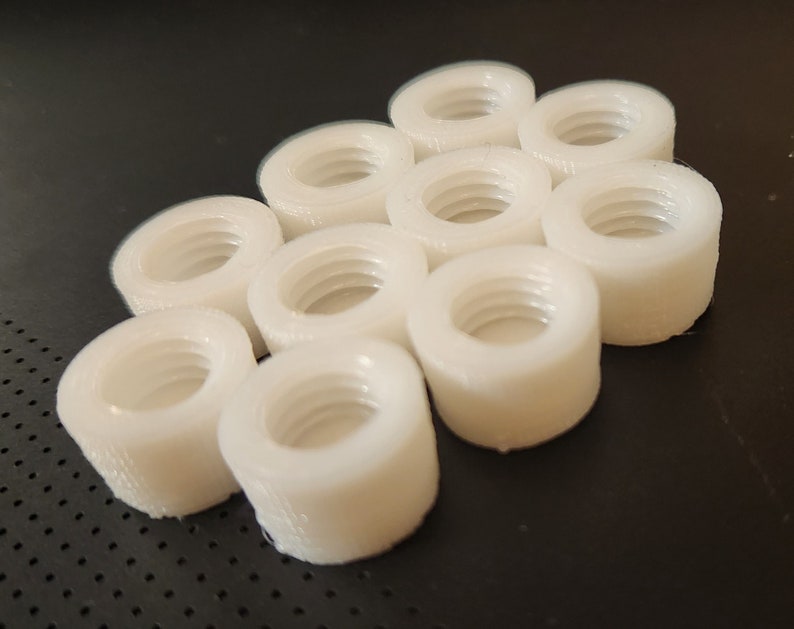 Puede incluir: Un grupo de 10 tuercas de pl&aacute;stico blanco, dispuestas en un patr&oacute;n hexagonal.