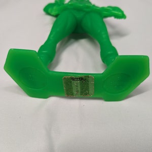 May include: Green plastic toy soldier with a rifle, standing on a green base with the word "SUPER" printed on it.