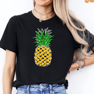 May include: A black t-shirt with a white outline of a pineapple with green leaves. The pineapple is made up of yellow hearts.