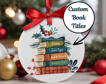 May include: A white round Christmas ornament with a stack of books with titles "Emma", "Jane Eyre", "Book Title 5", "Vanity Fair", and "Pride and Prejudice".