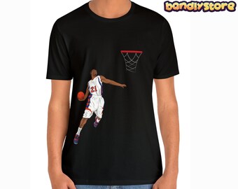 May include: Black t-shirt with a graphic of a basketball player in mid-air, about to dunk the ball. The player is wearing a white jersey with red and blue accents and the number 21 on the front. The graphic also includes a basketball hoop.