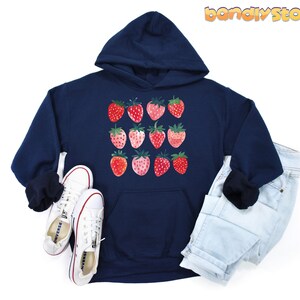 Pode incluir: Um moletom azul marinho com um gr&aacute;fico de morangos vermelhos e rosados na frente. O moletom tem um capuz com cord&atilde;o e um bolso canguru.