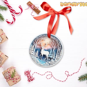 May include: A white papercraft deer ornament with a blue and white winter forest scene. The ornament is hanging from a red ribbon and is surrounded by Christmas decorations.