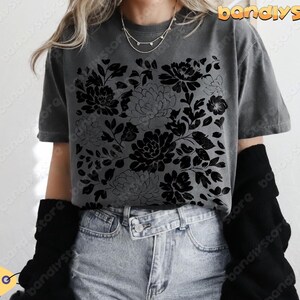 Woman wearing a charcoal Comfort Colors shirt with black linocut-style florals, styled with high-waisted shorts and layered jewelry.