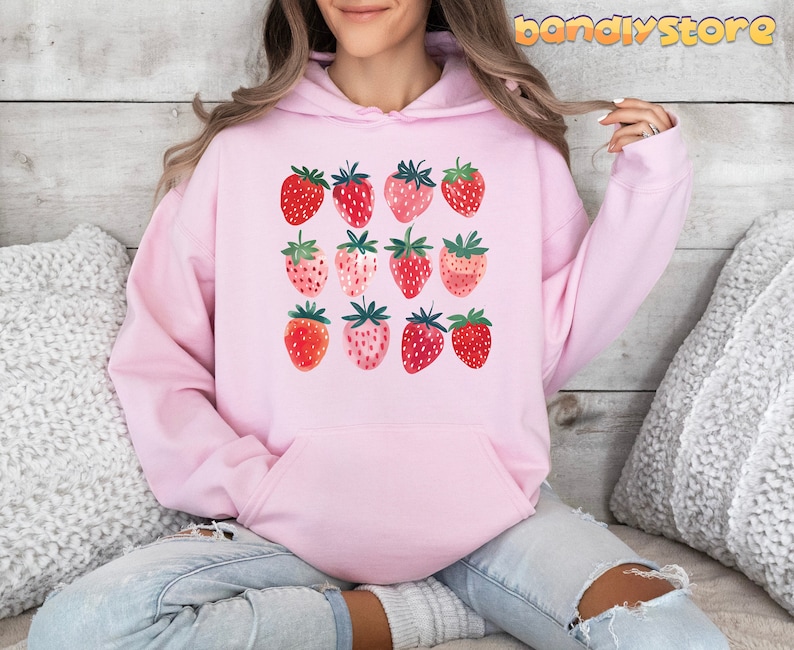 Pode incluir: Moletom rosa com estampa gr&aacute;fica de morangos em v&aacute;rios tons de vermelho e rosa.