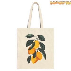 May include: A white canvas tote bag with a graphic of a lemon tree branch with yellow lemons and green leaves.