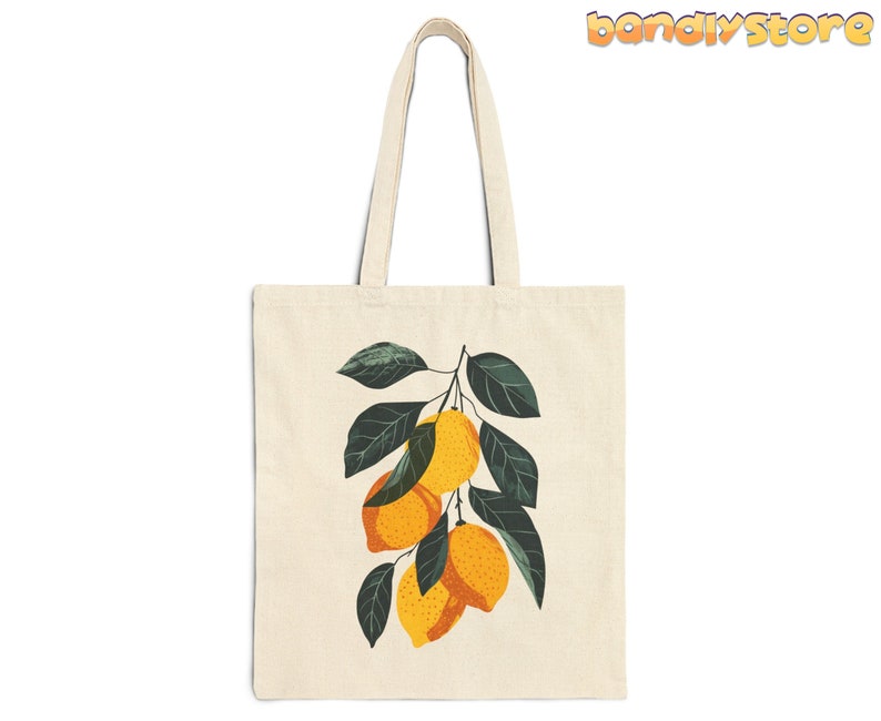 May include: A white canvas tote bag with a graphic of a lemon tree branch with yellow lemons and green leaves.