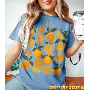 May include: A blue t-shirt with a graphic print of orange slices and leaves.