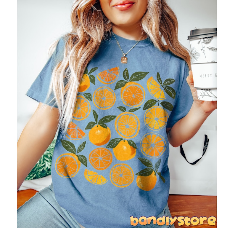 May include: A blue t-shirt with a graphic print of orange slices and leaves.