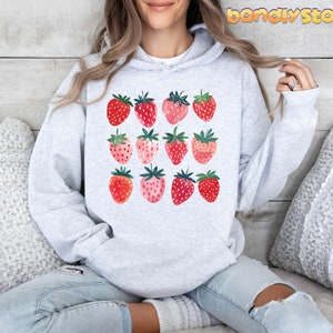 Pode incluir: Um moletom cinza com um gr&aacute;fico de morangos em tons de rosa e vermelho. Os morangos est&atilde;o dispostos em uma grade.