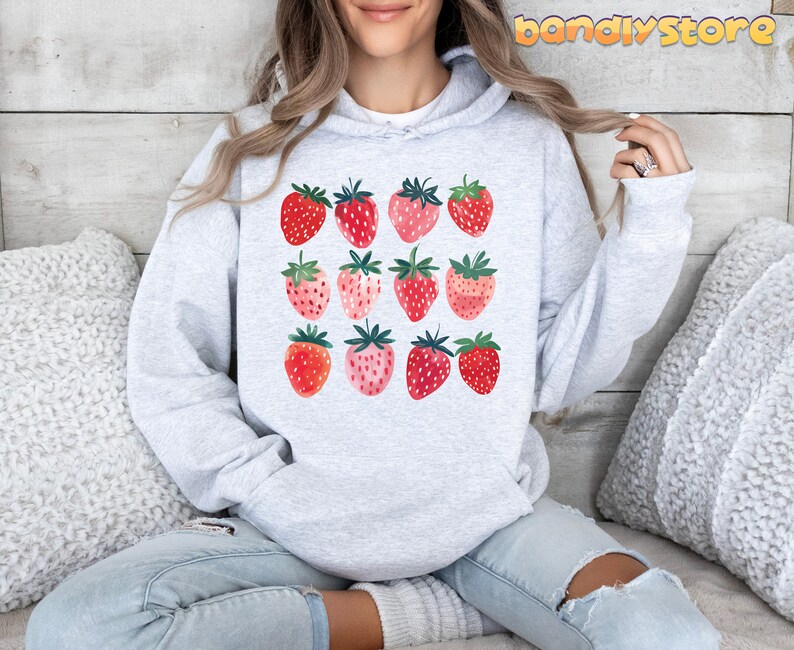 Pode incluir: Um moletom cinza com um gr&aacute;fico de morangos em tons de rosa e vermelho. Os morangos est&atilde;o dispostos em uma grade.