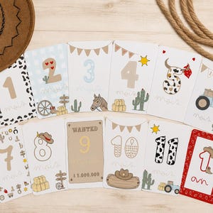 Peut inclure: Un ensemble de douze cartes étapes rectangulaires illustrées sur le thème western, numérotées de un à onze, avec une carte marquée '1 an'. Chaque carte présente des motifs variés comme des cactus, des chapeaux de cow-boy, des tracteurs et des chevaux.