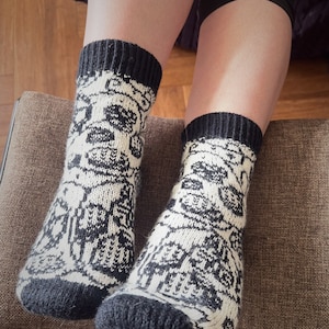 Peut inclure: Une paire de chaussettes en laine à motif noir et blanc avec un revers noir. Les chaussettes ont un motif géométrique.