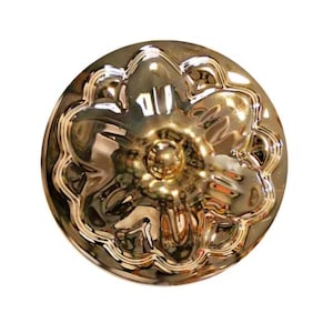 Peut inclure: Un bouton métallique doré de forme circulaire présentant un motif floral en relief avec cinq pétales arrondis rayonnant autour d'un dôme central. La surface possède une finition polie et réfléchissante qui capte la lumière.