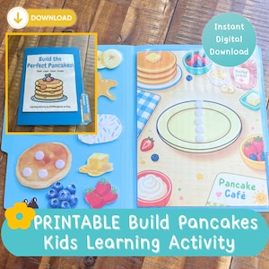 May include: A blue folder containing a printable pancake-themed learning activity. The cover features a pancake stack illustration and the text Build the Perfect Pancakes. Inside, a play mat shows a plate, toppings, and the text Pancake Café.