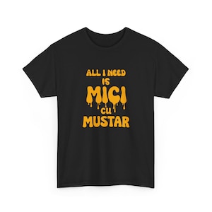 May include: Black t-shirt with the text "ALL I NEED IS mici cu MUSTAR" in orange, dripping font. The shirt is a short-sleeved crew neck style. The text is centered on the front of the shirt.