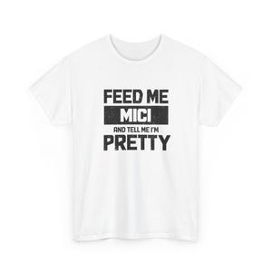 May include: White t-shirt with the text "FEED ME MICI AND TELL ME I'M PRETTY" in a distressed black font. The text is arranged in three lines, with "MICI" in a bold, centered block.