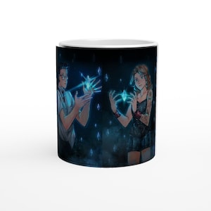 Pode incluir: Caneca de cerâmica branca com ilustração de fantasia. O design mostra um homem e uma mulher com cristais azuis brilhantes em um fundo azul escuro. Interior branco e acabamento brilhante, ideal para café ou chá.