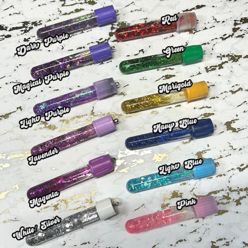 Pu&ograve; includere: Dieci piccoli flaconi di vetro pieni di glitter, ognuno con un colore diverso e un tappo a vite. I colori sono viola scuro, viola magico, viola chiaro, lavanda, magenta, bianco/argento, rosso, verde, calendula, blu navy, blu chiaro e rosa.