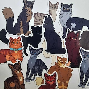 Op de afbeelding: Een verzameling kattenstickers in verschillende kleuren en poses. De stickers tonen gedetailleerde illustraties van katten, waaronder tabby-, zwarte en oranje katten. Sommige katten hebben halsbanden, allemaal tegen een witte achtergrond.