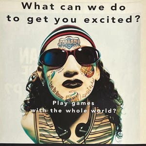 May include: An advert with a person's face covered in logos and text, including "JEOPARDY ONLINE" and "WHEEL OF FORTUNE." The text asks "What can we do to get you excited?" and "Play games with the whole world?" Headphones are visible.