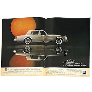May include: A silver Cadillac Seville car is parked in front of a sunset. The car is reflecting in a puddle of water. The text "A new expression of Cadillac excellence." is at the bottom of the page. The text "Seville by Cadillac. At home anywhere in the world." is at the bottom of the right page. The General Motors logo is in the bottom right corner.