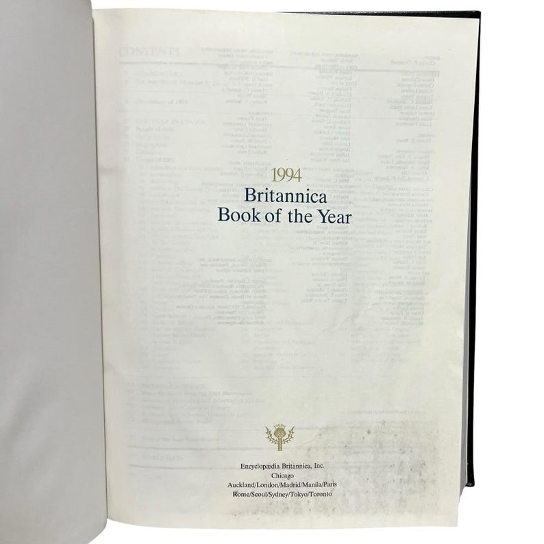 May include: Open book with the title "1994 Britannica Book of the Year" on the right page. The book's pages are off-white, and the text is in black. The book's spine is black. The publisher's information is at the bottom.