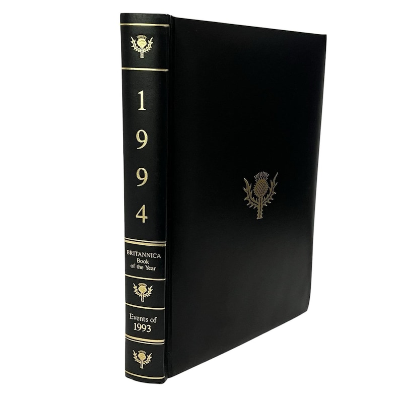 May include: A black "Britannica Book of the Year" from 1994. The spine features the year and gold accents. The cover has a gold thistle emblem.