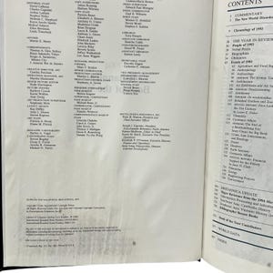 May include: An open book displaying the "CONTENTS" section, with a list of topics including "The Year in Review" and "Britannica Update." The pages are filled with text and titles.