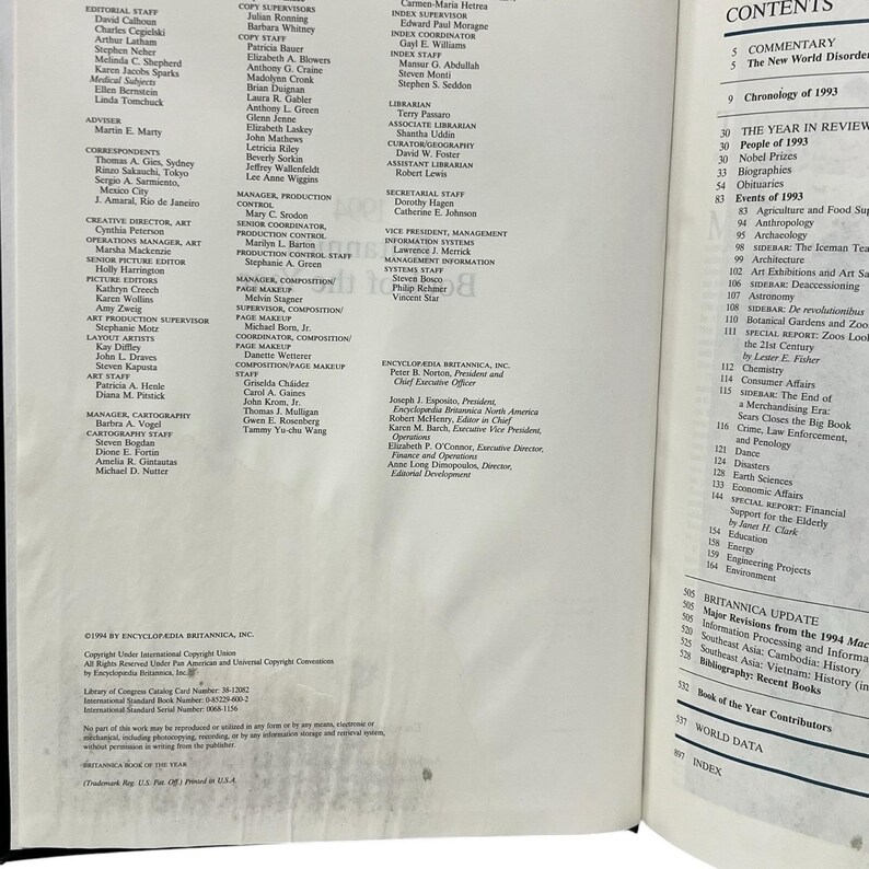 May include: An open book displaying the "CONTENTS" section, with a list of topics including "The Year in Review" and "Britannica Update." The pages are filled with text and titles.